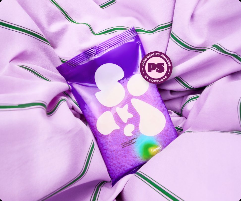 Flewd Fatigue Defeating stresscare bath soak pouch on a lilac striped sheet with a PopSugar award badge