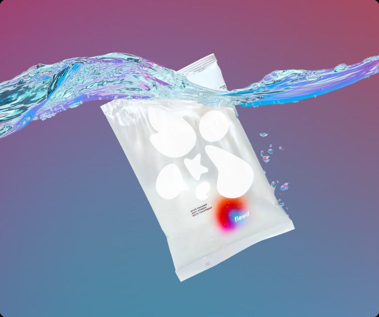 Flewd Ache Erasing magnesium bath soak pouch splashing into water on a purple and blue background
